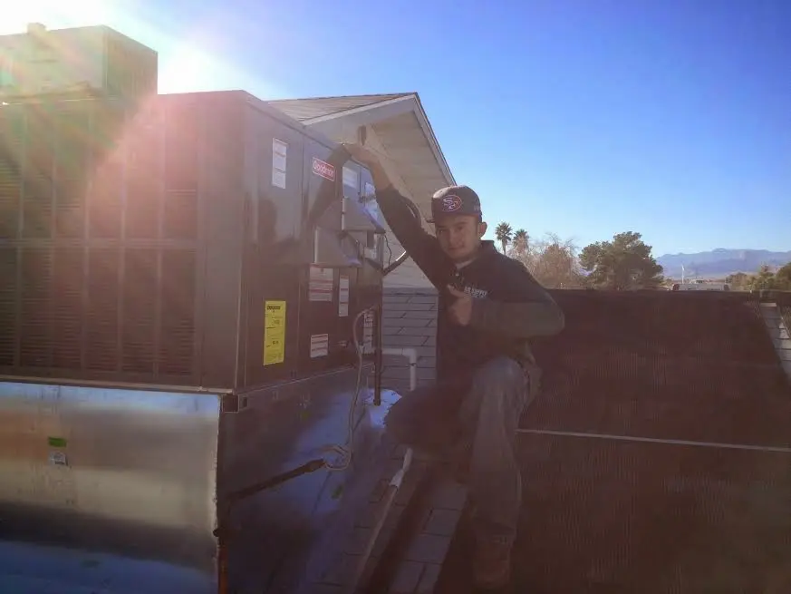 HVAC technician performing AC Tune-Up on a rooftop unit in Indiantown