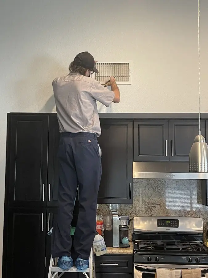 Technician inspecting an air vent during HVAC service in Indiantown